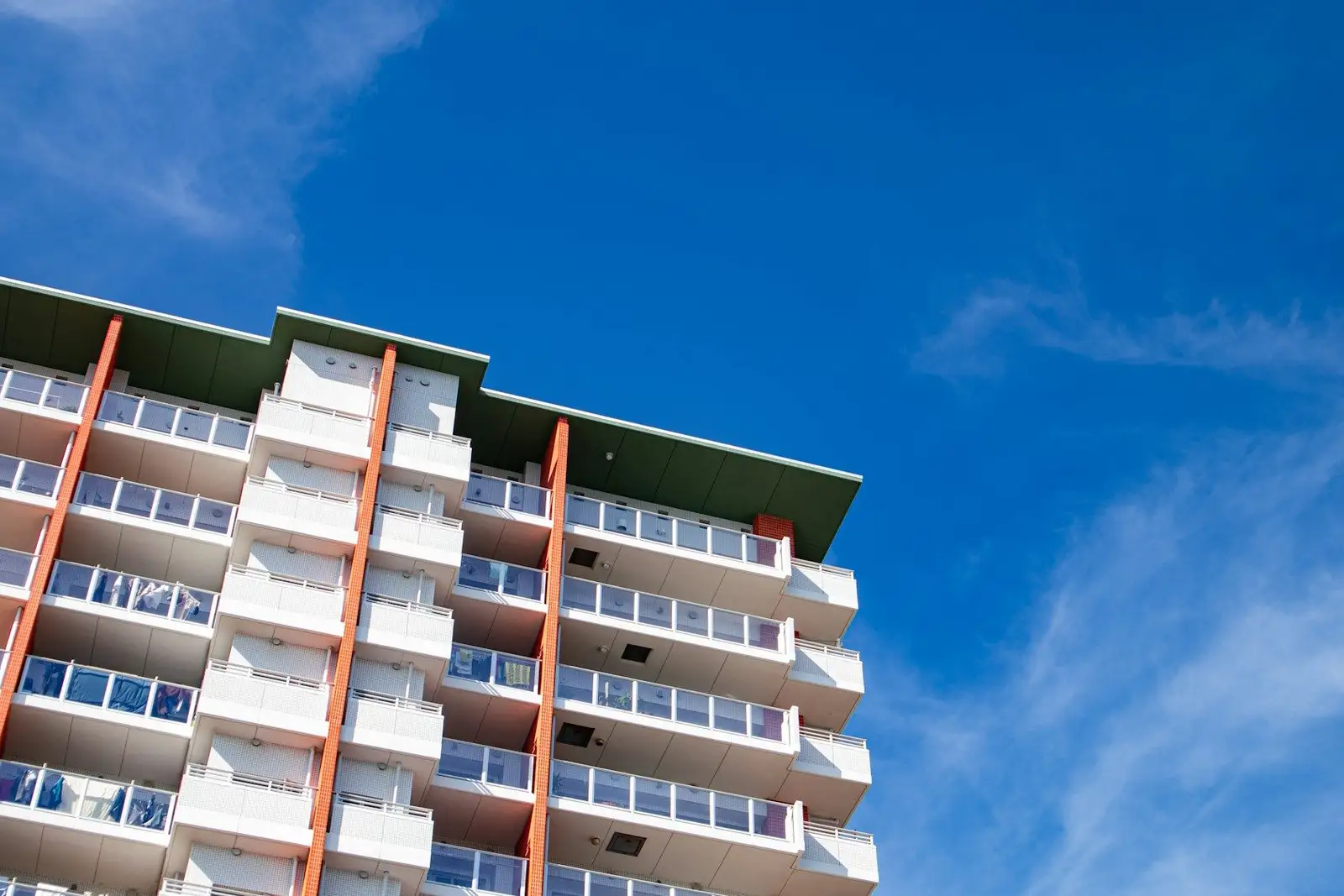 White residential tower with orange vertical accents under a blue sky