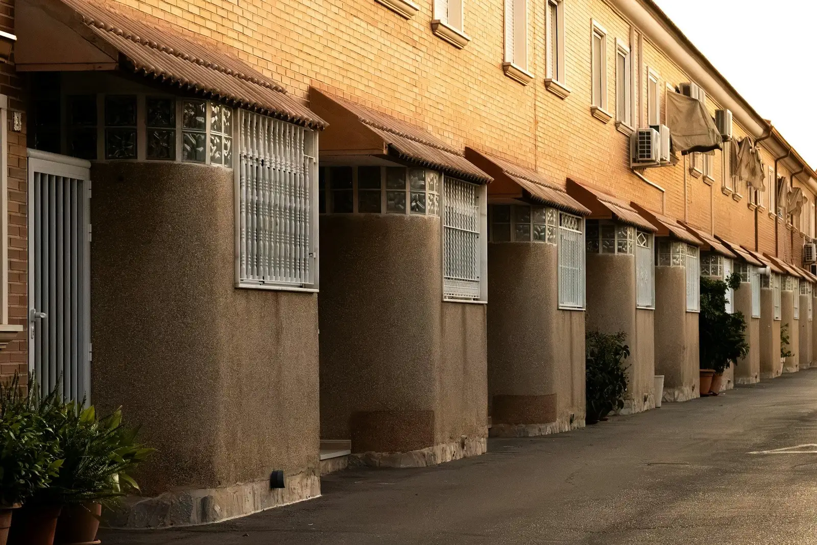 Row of brick townhouses with rounded front walls and window grilles