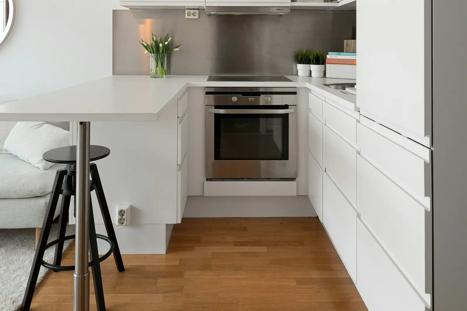 Compact white kitchen with a breakfast counter and a stool
