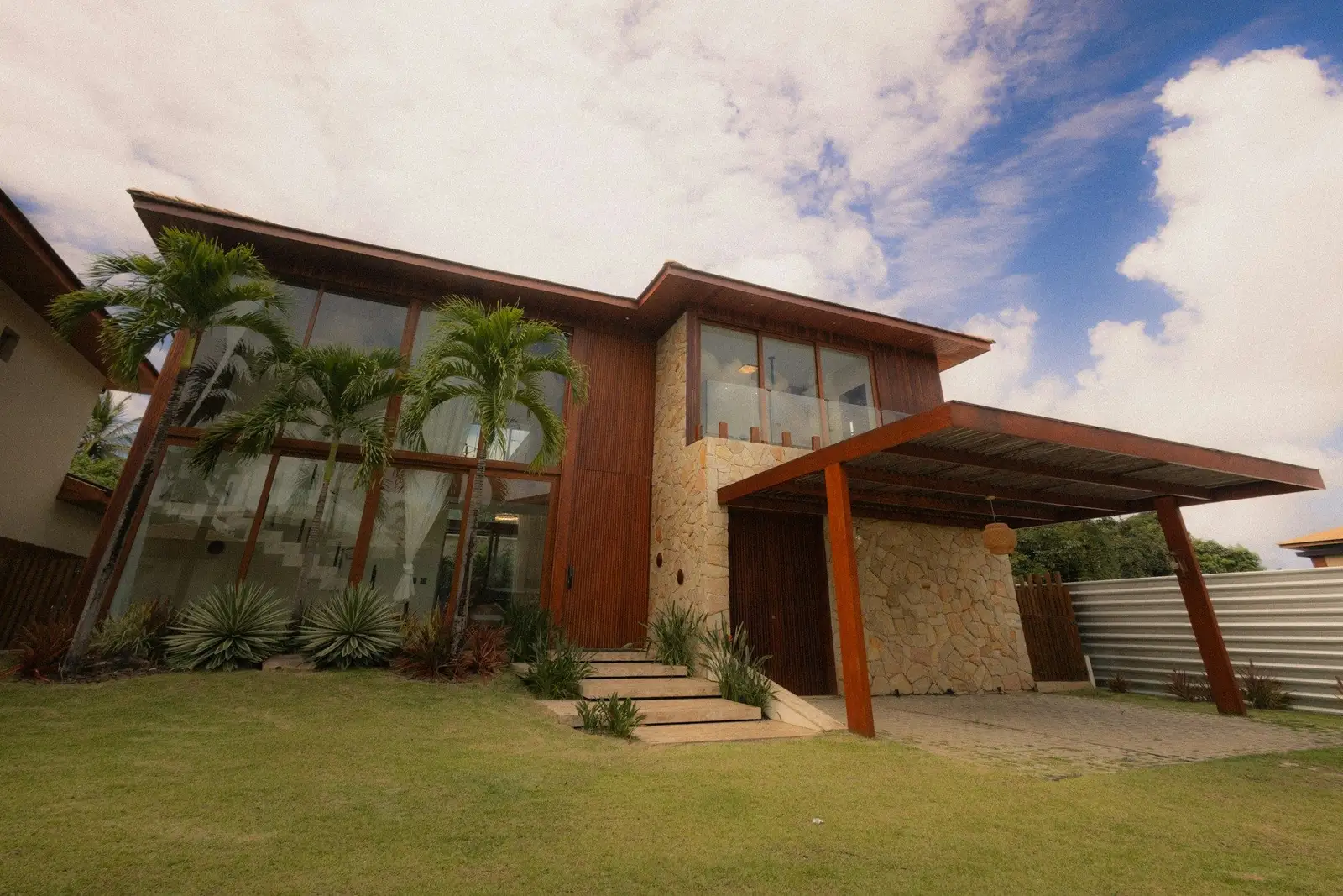 Two-storey house with timber cladding, tall glass and palms