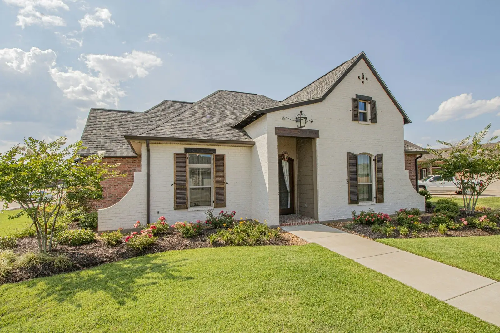 White brick house with shutters and a front lawn