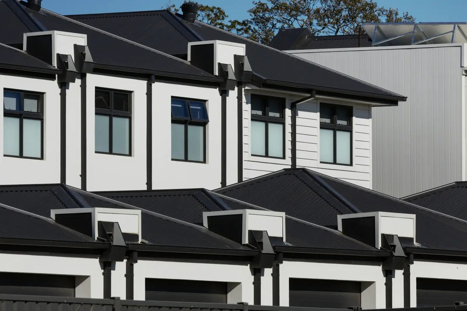 White townhouses with dark roofs and dormer windows