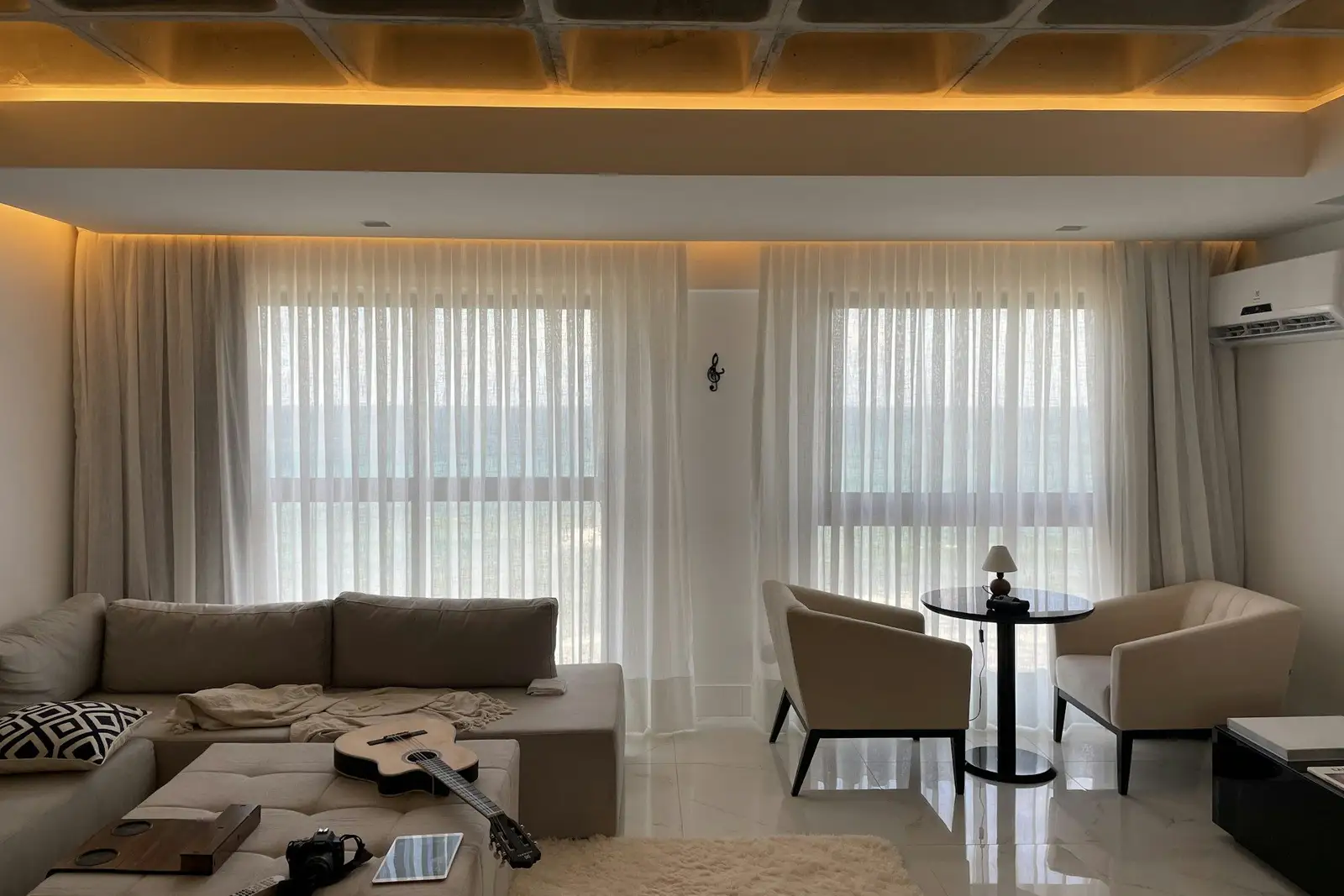 Living room with a beige sofa, two armchairs and sheer curtains