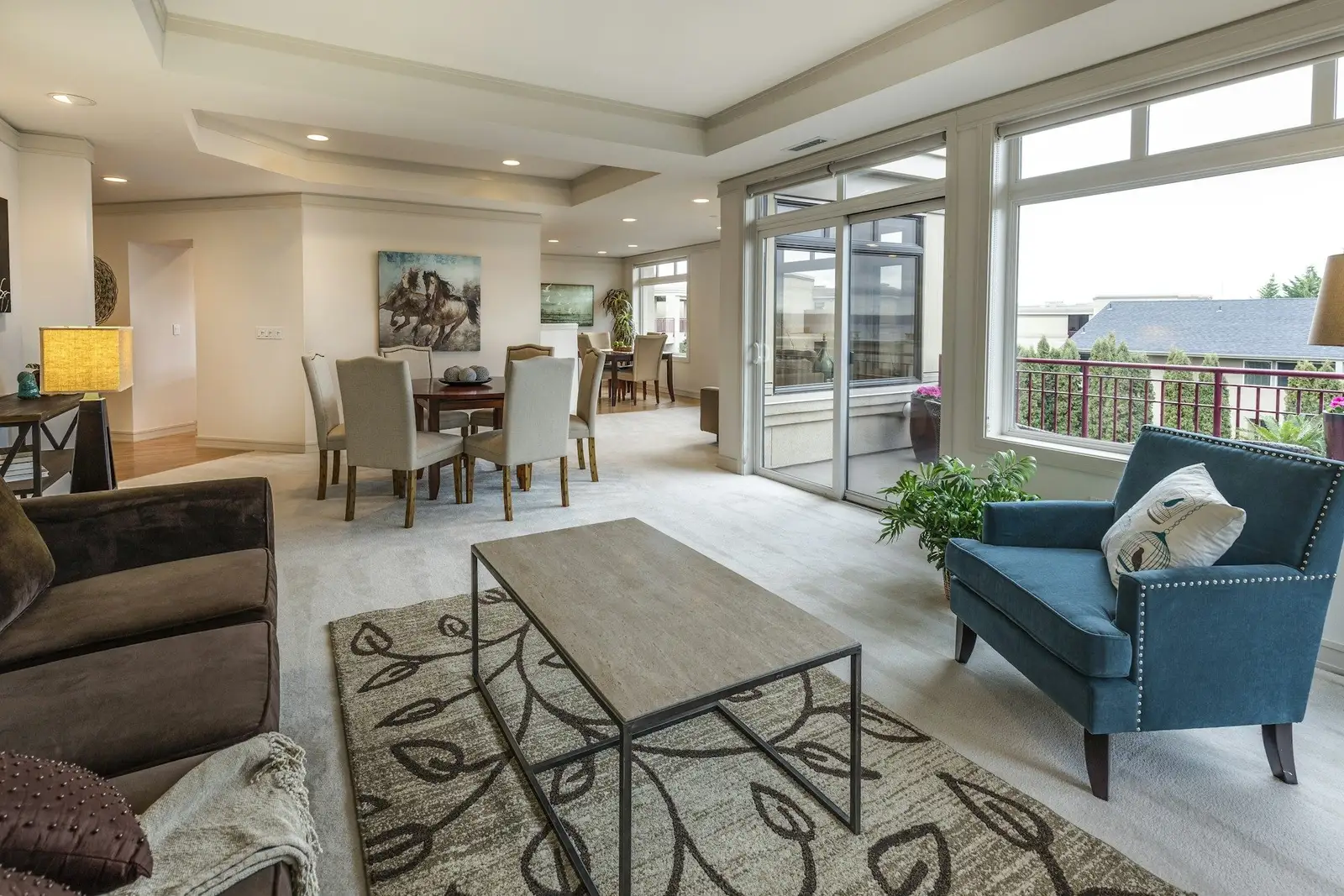 Open living and dining area with a blue armchair and wide windows