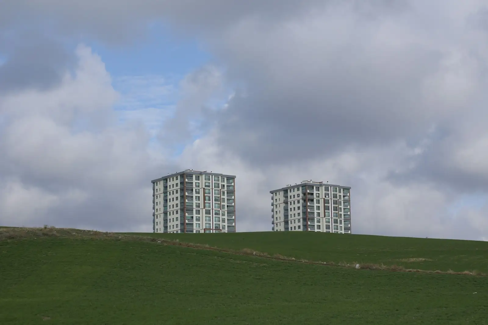 Green open land with two apartment towers in the distance