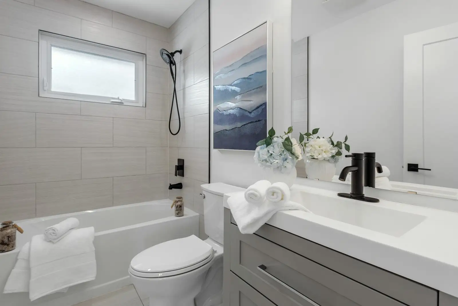 Bathroom with a tub-shower, a white vanity and towels
