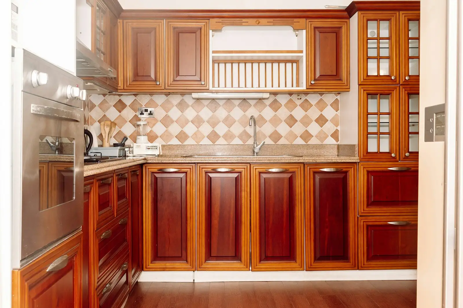 Kitchen with red-brown wooden cabinets and a tiled backsplash