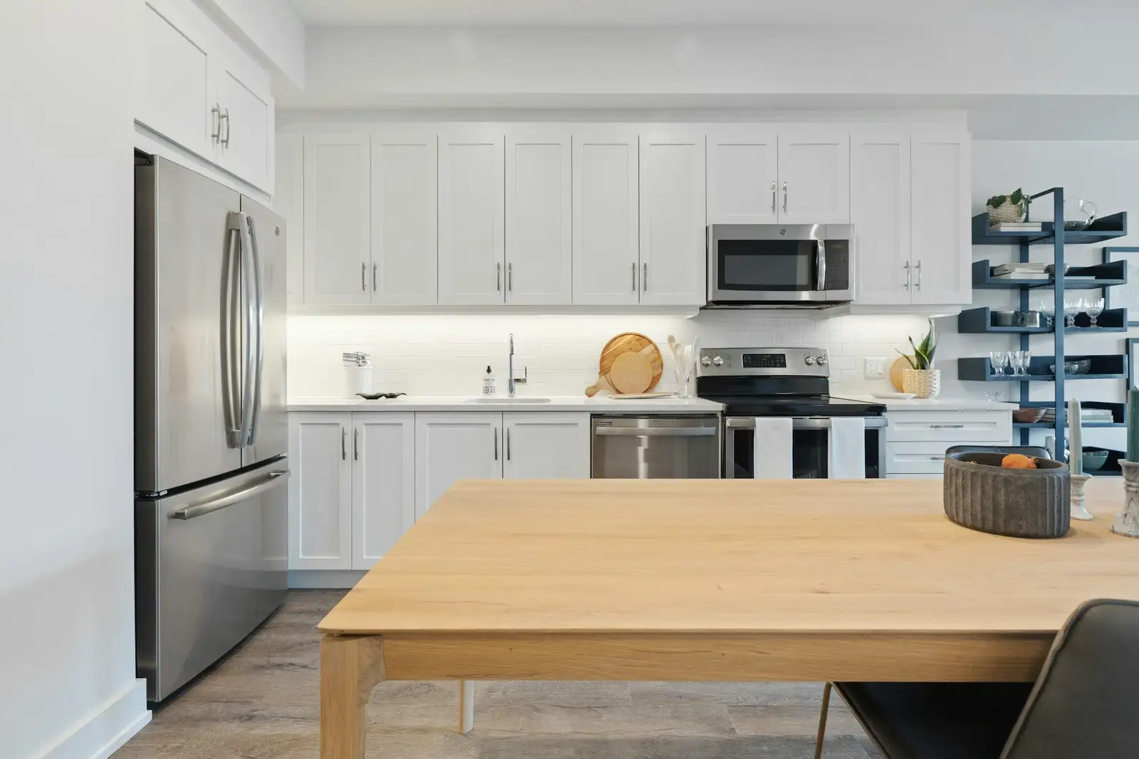 White kitchen with a stainless fridge and a wooden table