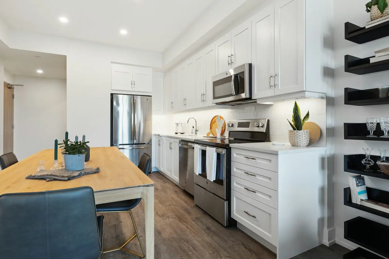 White kitchen with a wooden dining table and wall shelves